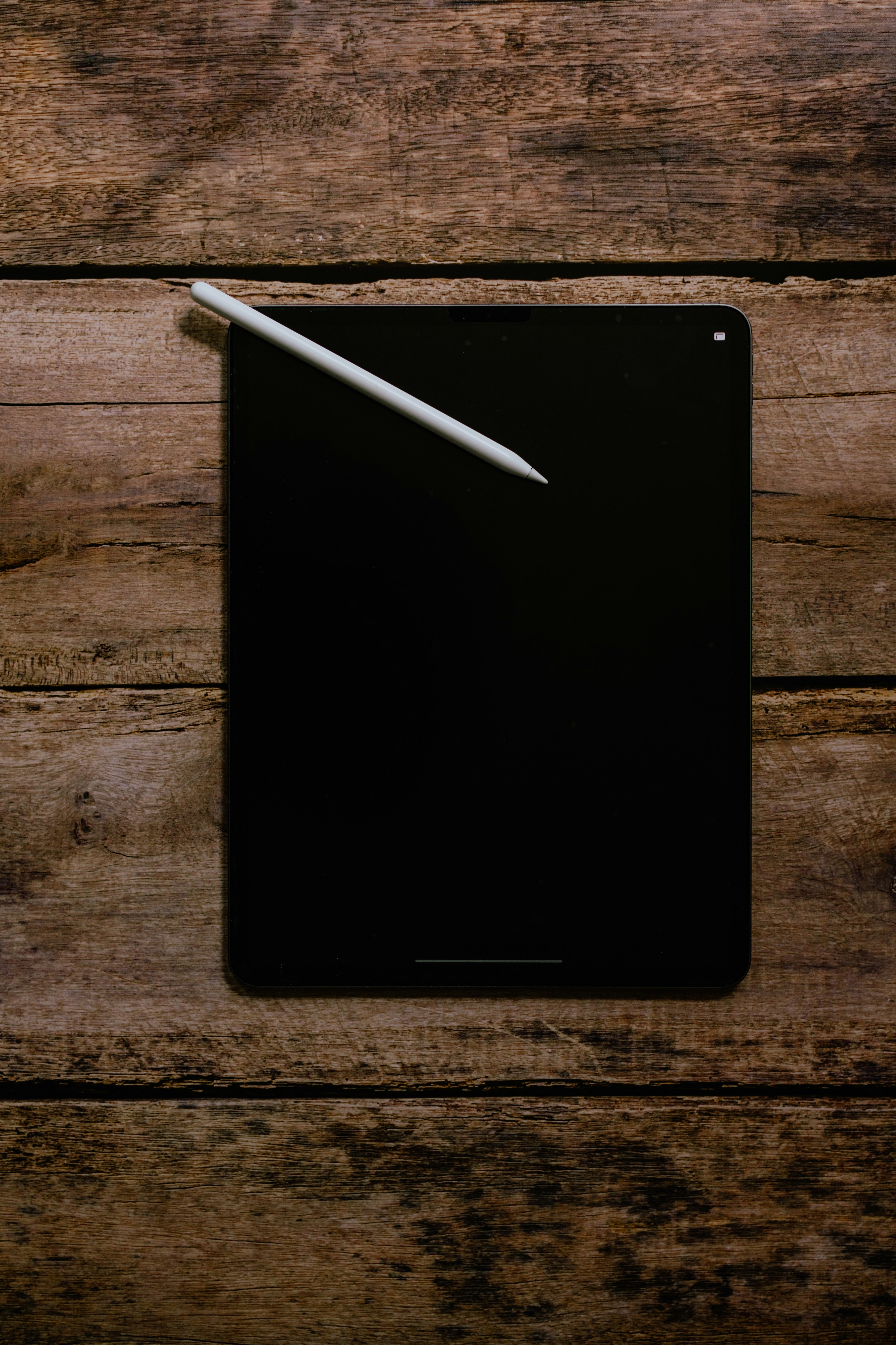 black ipad on brown wooden table